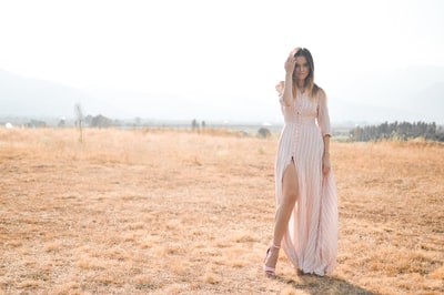 Wearing skirt woman standing in the fields under the blue sky
